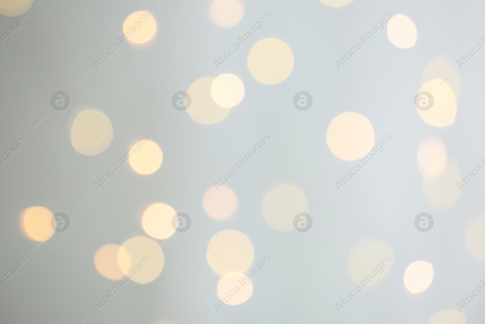 Photo of Blurred view of festive lights on light grey background. Bokeh effect