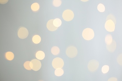 Photo of Blurred view of festive lights on light grey background. Bokeh effect