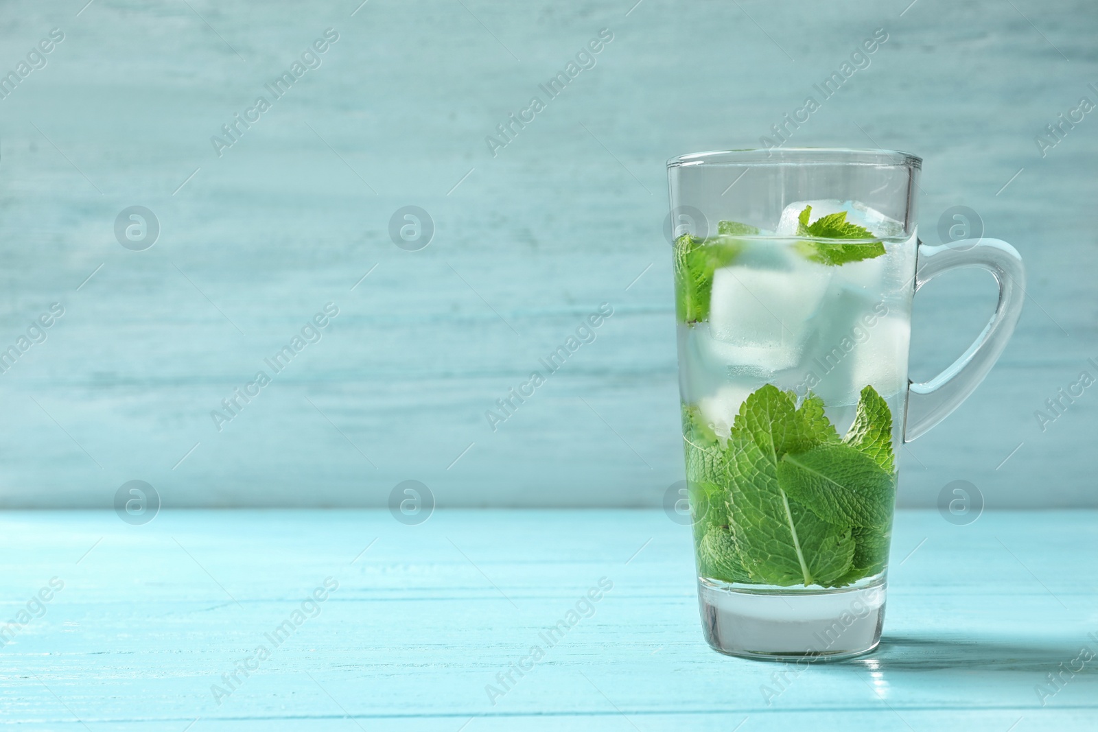 Photo of Cup with aromatic mint tea and fresh leaves on table