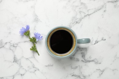 Photo of Cup of delicious chicory drink and flowers on white marble table, flat lay