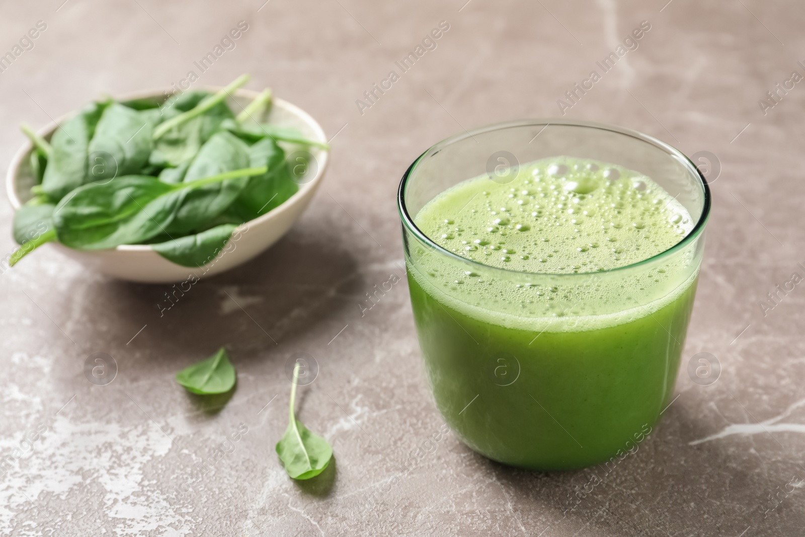 Photo of Glass with delicious detox juice and spinach on table