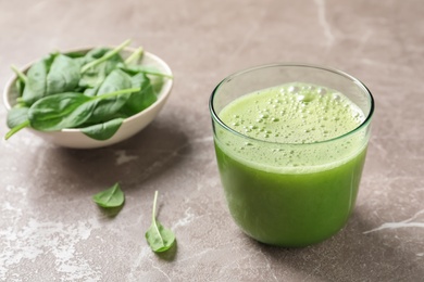 Photo of Glass with delicious detox juice and spinach on table