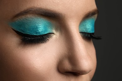 Photo of Young woman with evening makeup on grey background, closeup. Eye shadow product