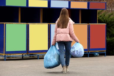 Woman with garbage at recycling point outdoors, back view