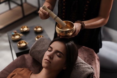 Woman at healing session with singing bowl in dark room