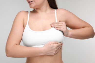 Mammology. Woman doing breast self-examination on light grey background, closeup