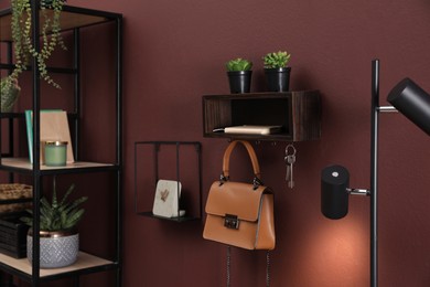 Wooden key holder with bag and houseplants on wall in room