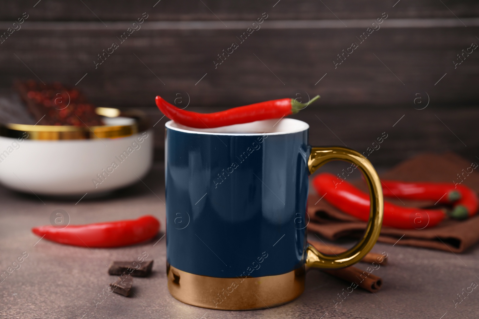 Photo of Cup of hot chocolate with chili pepper on grey table