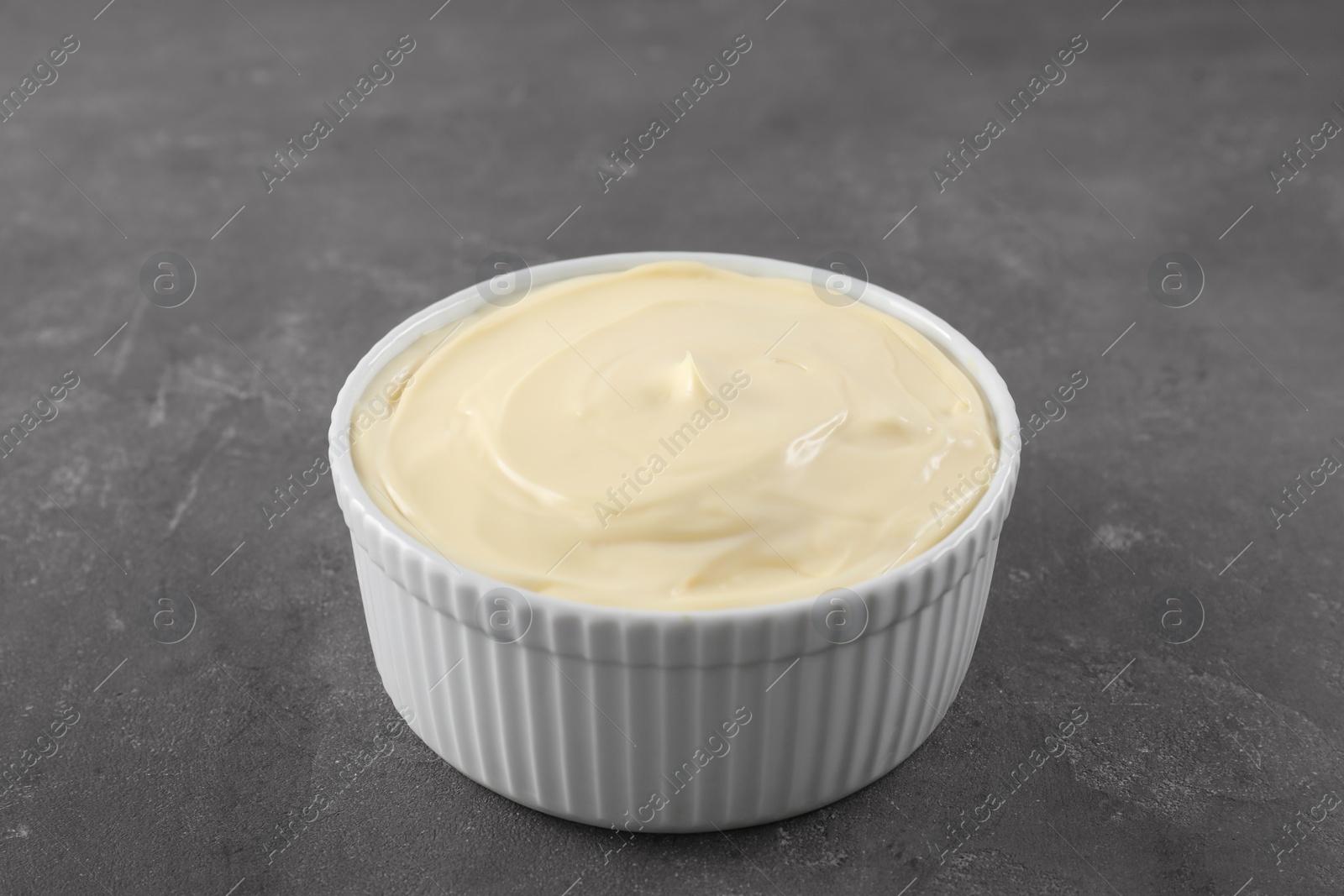 Photo of Fresh mayonnaise sauce in bowl on grey table