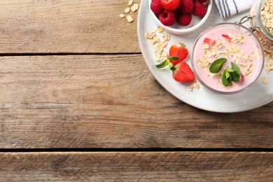 Photo of Glass of tasty berry smoothie with oatmeal on wooden table, top view. Space for text