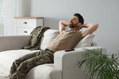 Photo of Soldier napping on soft sofa in living room. Military service