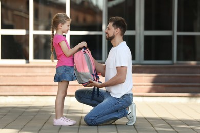 Photo of Happy father preparing his daughter to school outdoors