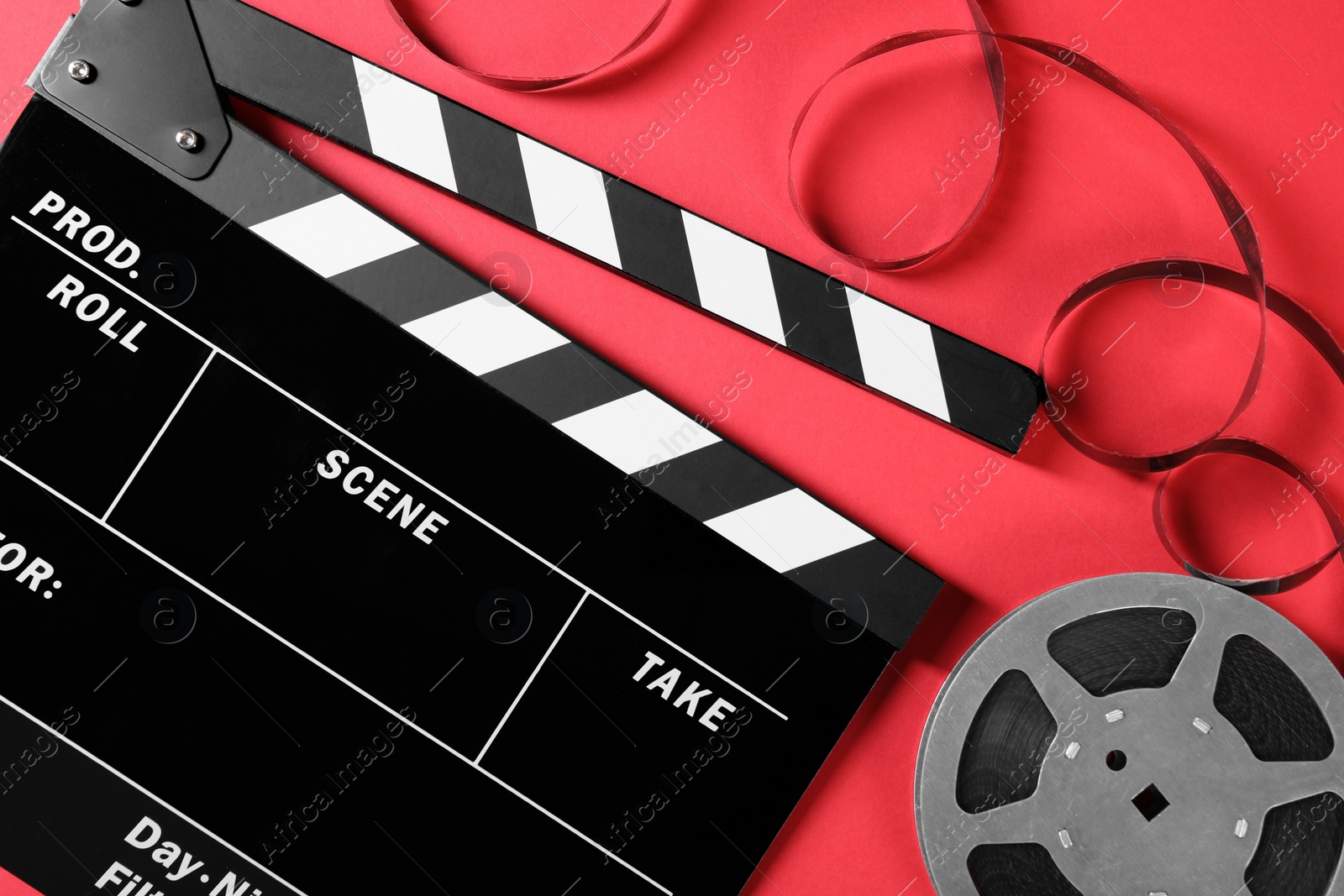 Photo of Clapperboard and film reel on red background, flat lay