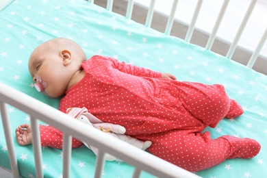 Cute baby girl sleeping in crib at home