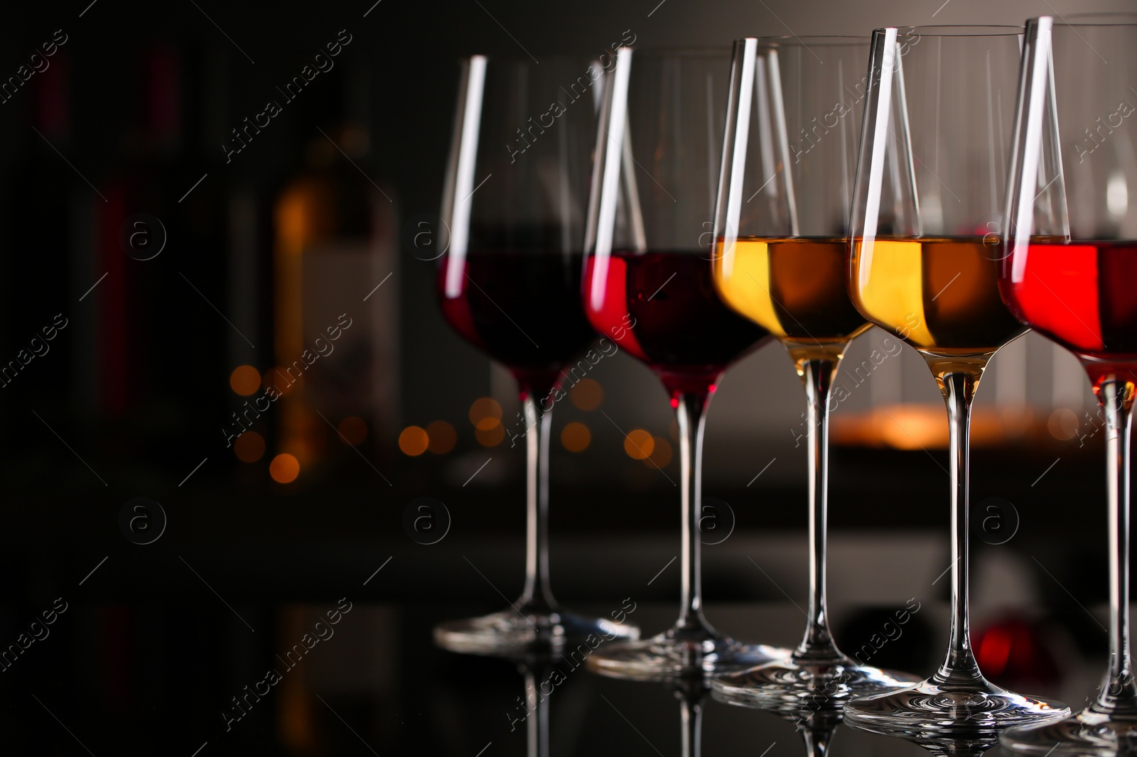 Photo of Row of glasses with different wines on bar counter against blurred background. Space for text