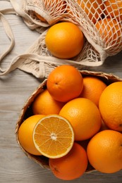 Many whole and cut oranges on wooden table, flat lay