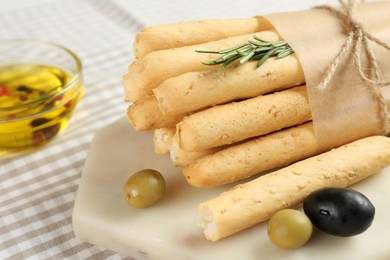 Photo of Tasty grissini with rosemary, olives and oil on table, closeup