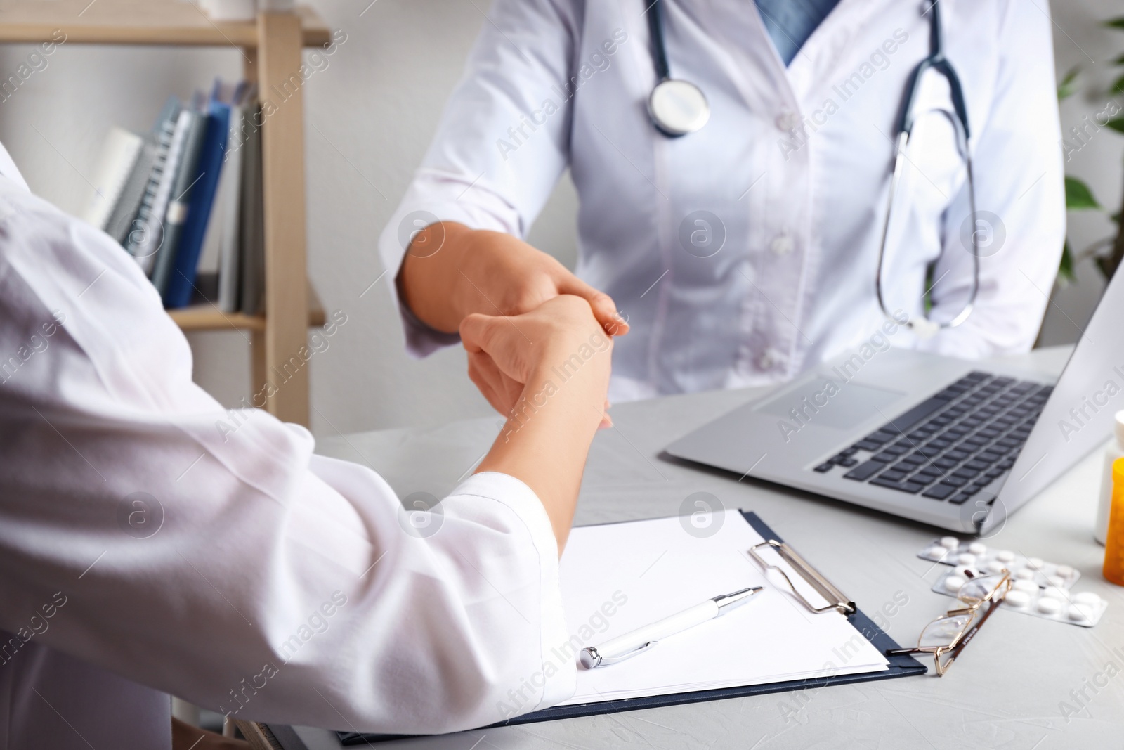 Photo of Doctors shaking hands in office, closeup. Medical service