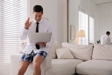 Photo of Man in shirt and underwear working on laptop indoors. Stay at home concept