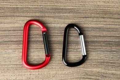 Photo of Two metal carabiners on wooden table, flat lay