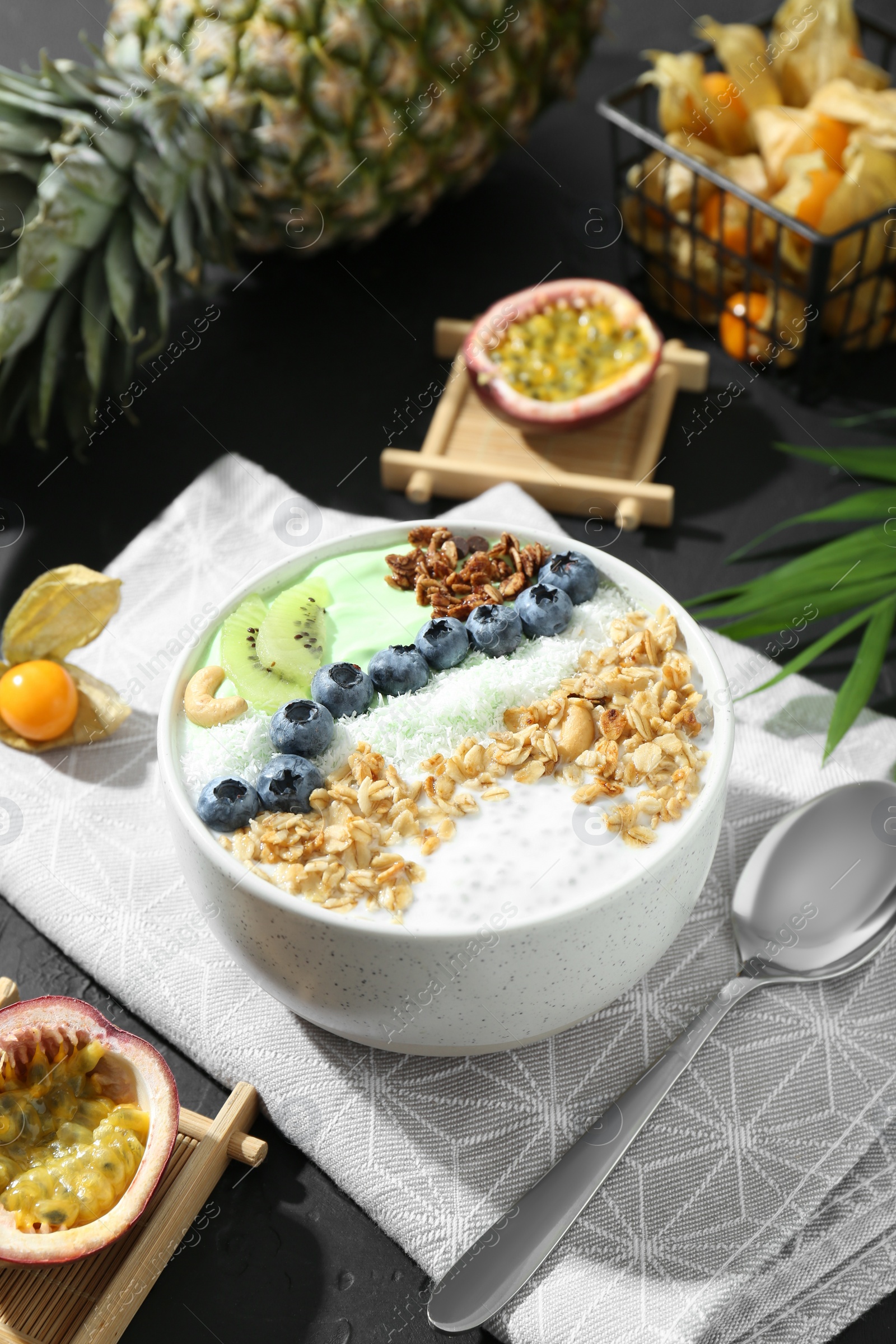 Photo of Tasty smoothie bowl with fresh kiwi fruit, blueberries and oatmeal served on black table