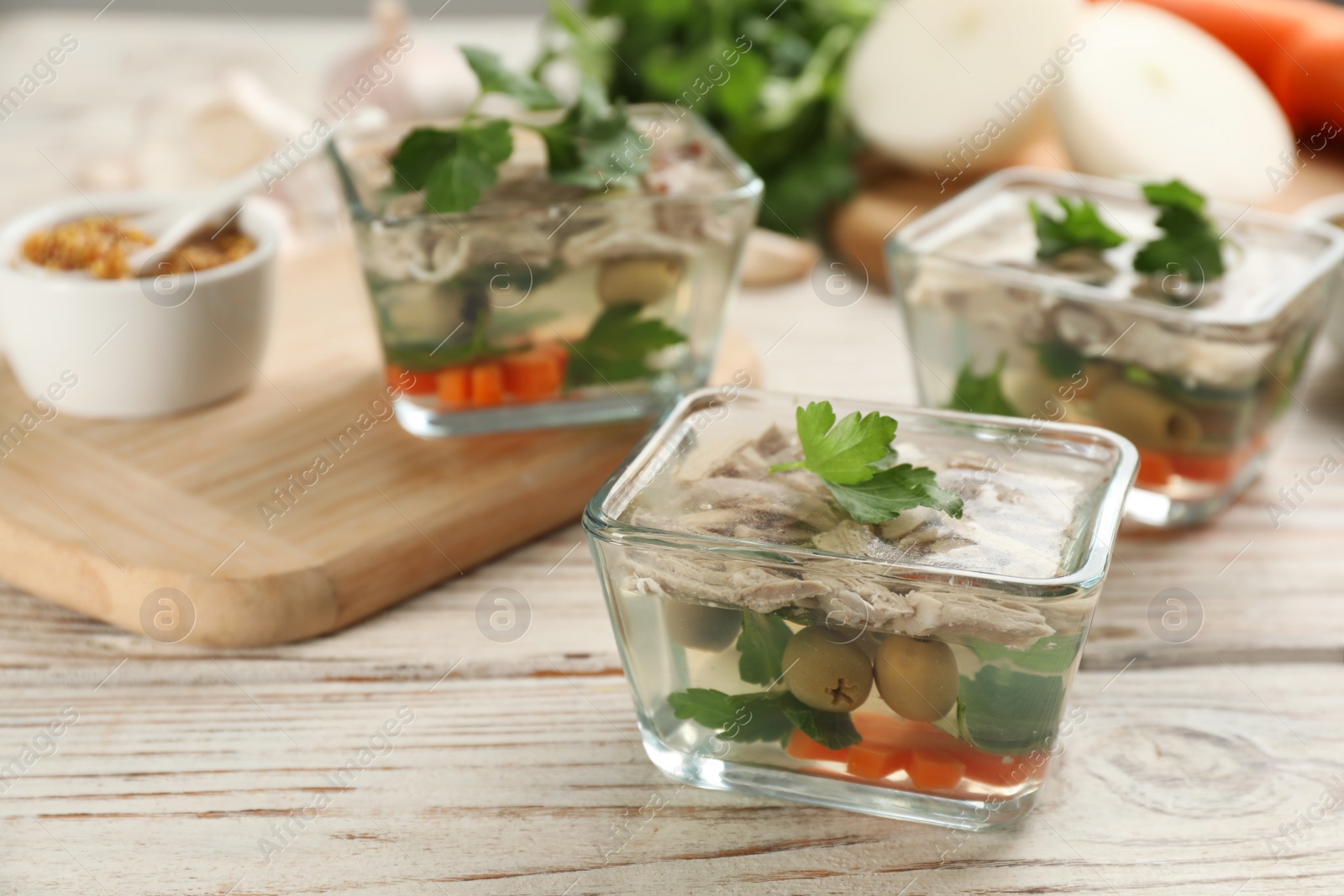 Photo of Delicious aspic in glass bowl on white wooden table