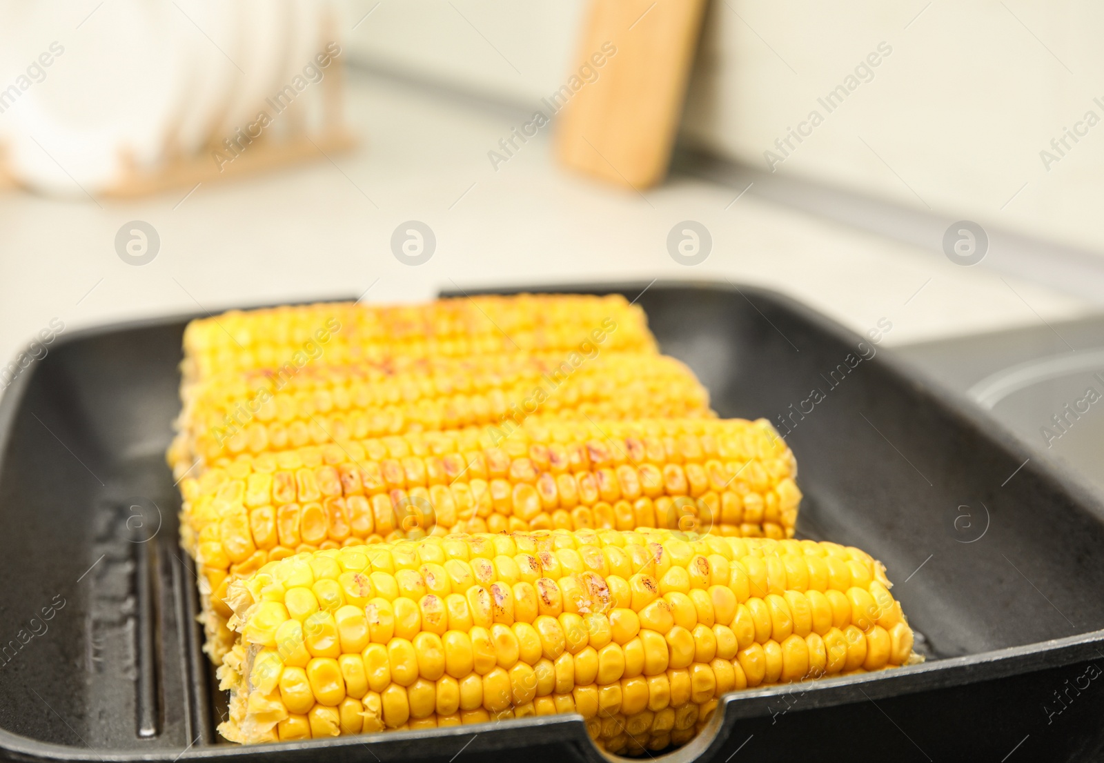 Photo of Fresh corn cobs on grill pan, closeup