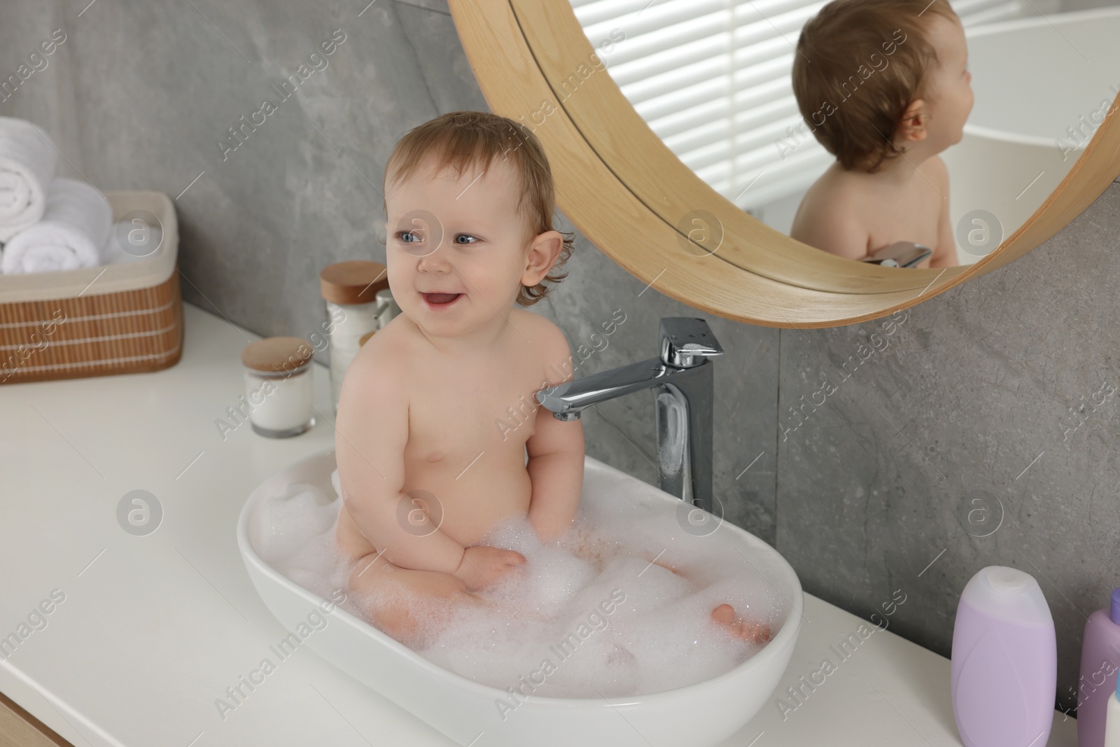 Photo of Cute little baby bathing in sink at home