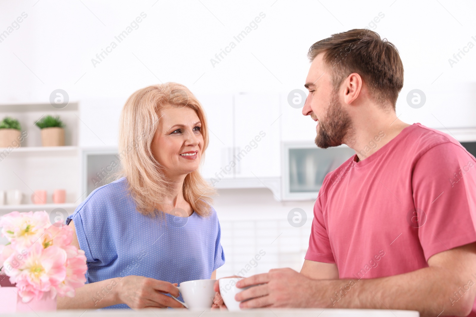 Photo of Young man and his mature mom having breakfast in kitchen. Happy Mother's Day
