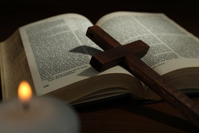 Photo of Cross, Bible and church candle on wooden table