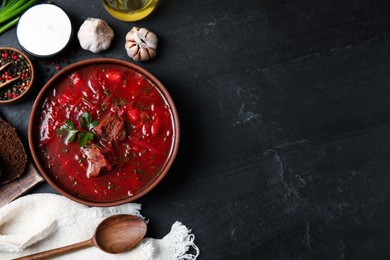 Stylish brown clay bowl with Ukrainian borsch served on black table, flat lay. Space for text