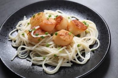 Delicious scallop pasta with green onion on grey table, closeup