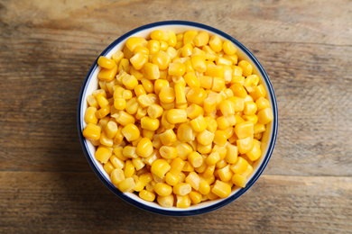 Photo of Delicious canned corn in bowl on wooden table, top view