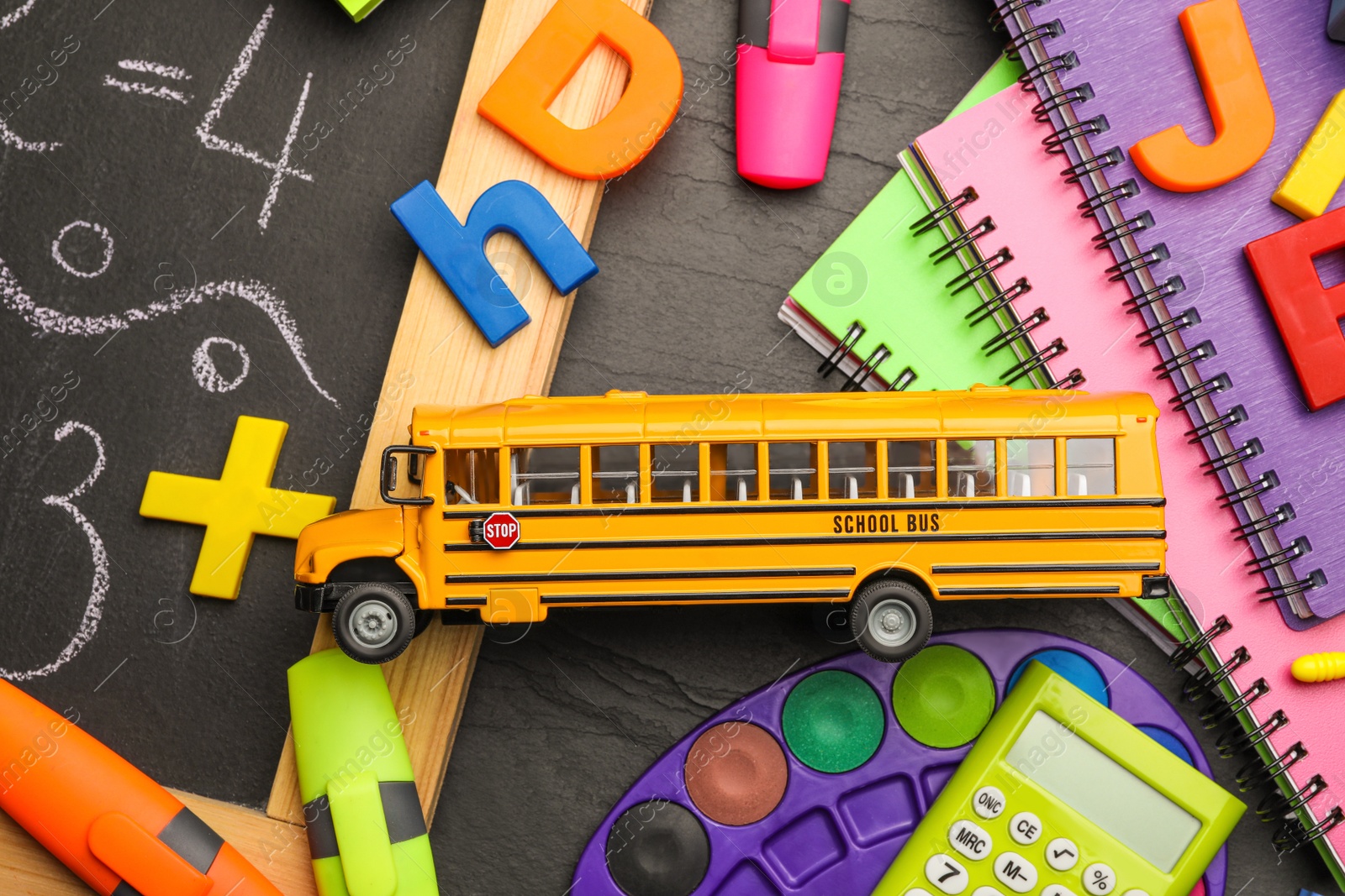 Photo of Flat lay composition with yellow school bus model on black background. Transport for students