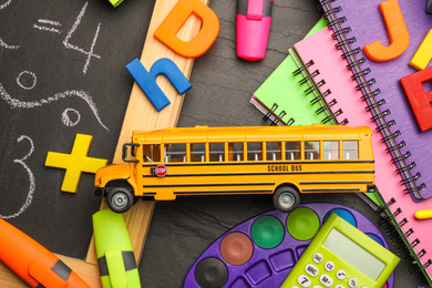 Photo of Flat lay composition with yellow school bus model on black background. Transport for students
