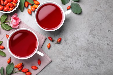 Photo of Fresh rose hip tea and berries on grey table, flat lay. Space for text