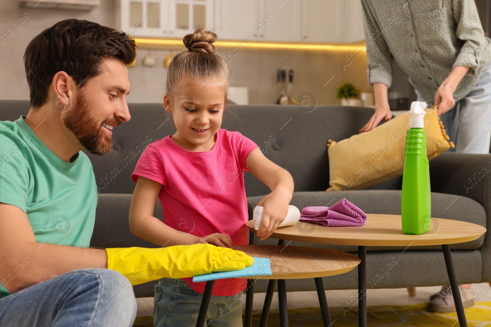 Photo of Spring cleaning. Parents with their daughter tidying up living room together