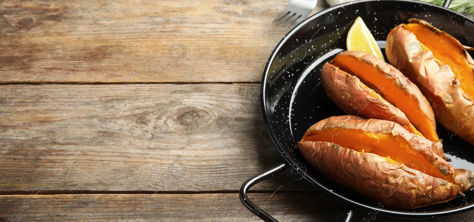 Image of Tasty baked sweet potatoes on wooden table, space for text. Banner design