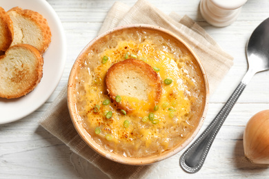 Tasty homemade french onion soup served on white wooden table, flat lay