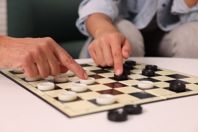 Photo of Women playing checkers at white table, closeup