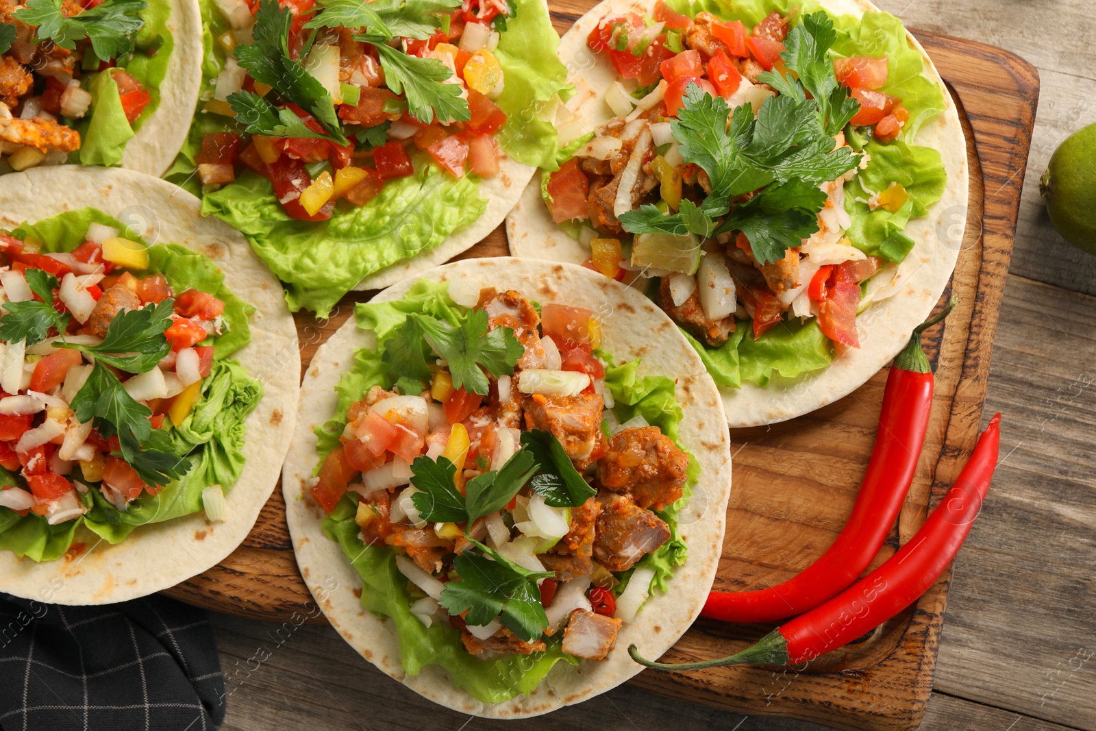Photo of Delicious tacos with vegetables and meat on wooden table, flat lay