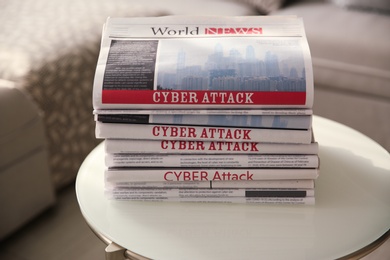 Stack of newspapers with headlines CYBER ATTACK on table indoors