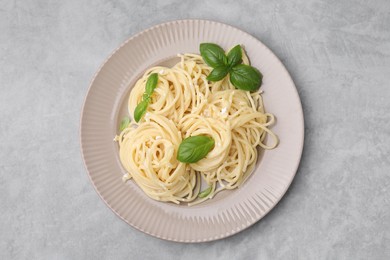 Photo of Delicious pasta with brie cheese and basil leaves on grey textured table, top view