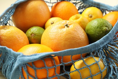 Photo of String bag with different fruits on beige background, closeup