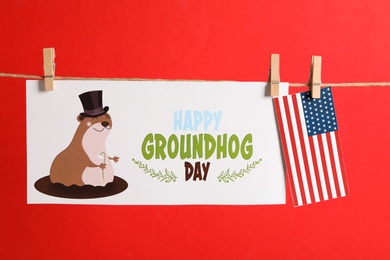 Photo of Happy Groundhog Day greeting card and American flag hanging on red background