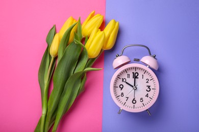 Photo of Pink alarm clock and beautiful tulips on color background, flat lay. Spring time