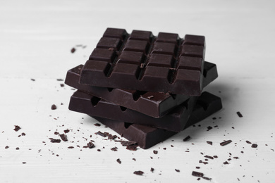 Tasty dark chocolate bars on white table