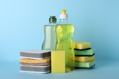 Photo of Sponges and other cleaning products on light blue background