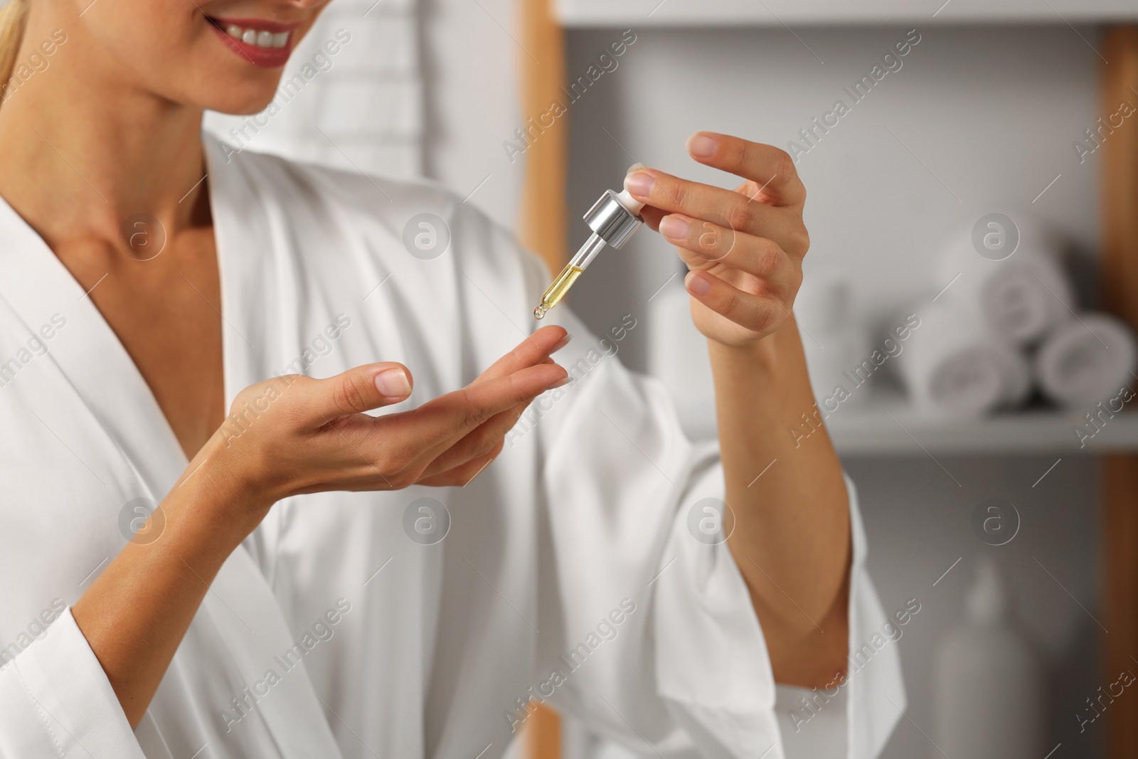 Photo of Woman applying cosmetic serum onto her hand in bathroom, closeup