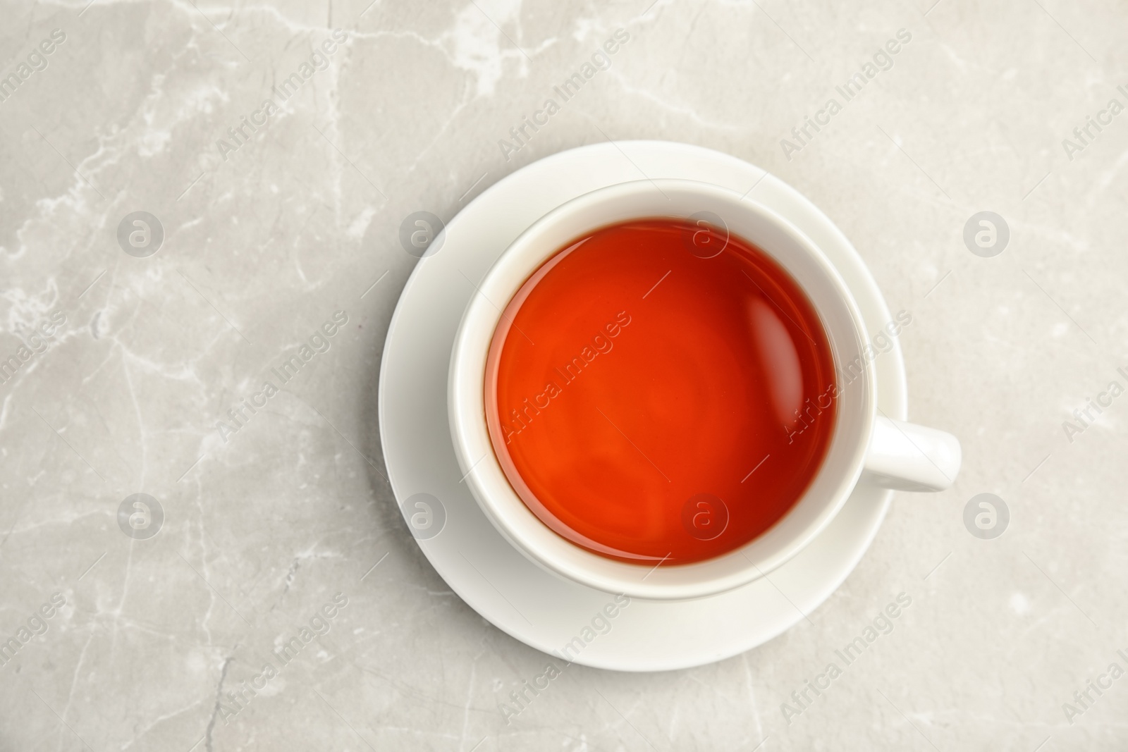 Photo of Porcelain cup of black tea on table, top view